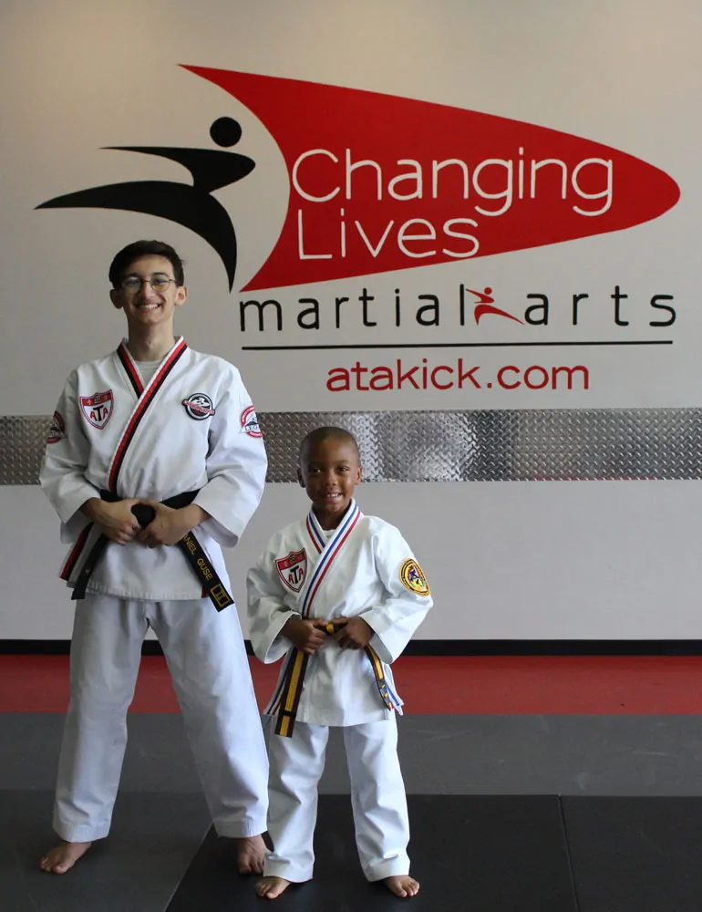 Young martial arts students in uniform celebrating their progress together